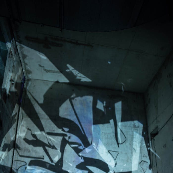 shards of a glass mirror cast blue shadows onto a concrete wall