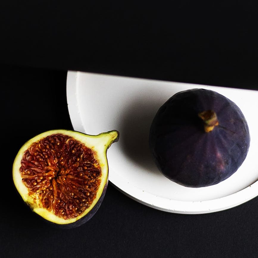 figs cut open figs on a white plate against a dark backdrop